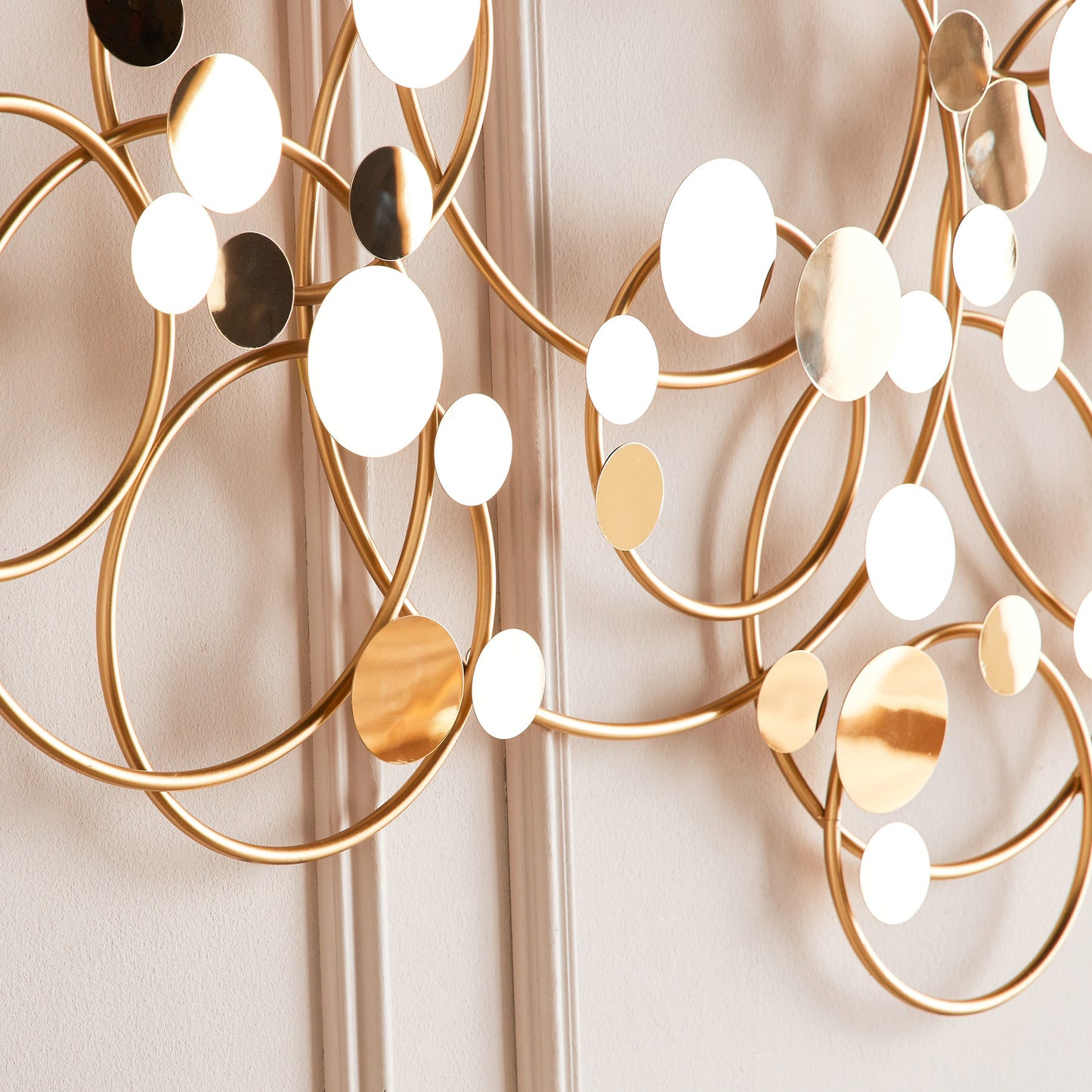 Decorative wall light fixture with gold and white elements on a neutral background