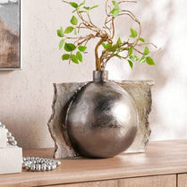 Decorative vase with a plant on a wooden surface with a neutral background