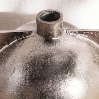 Metallic object with a cylindrical top on a reflective surface