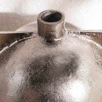 Metallic object with a cylindrical top on a reflective surface