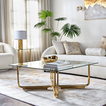 Modern living room with a gold coffee table, white sofa, and decorative plants.