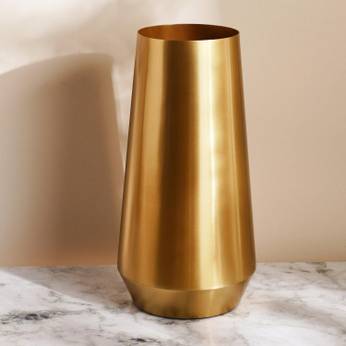Gold vase on a marble surface with a beige background