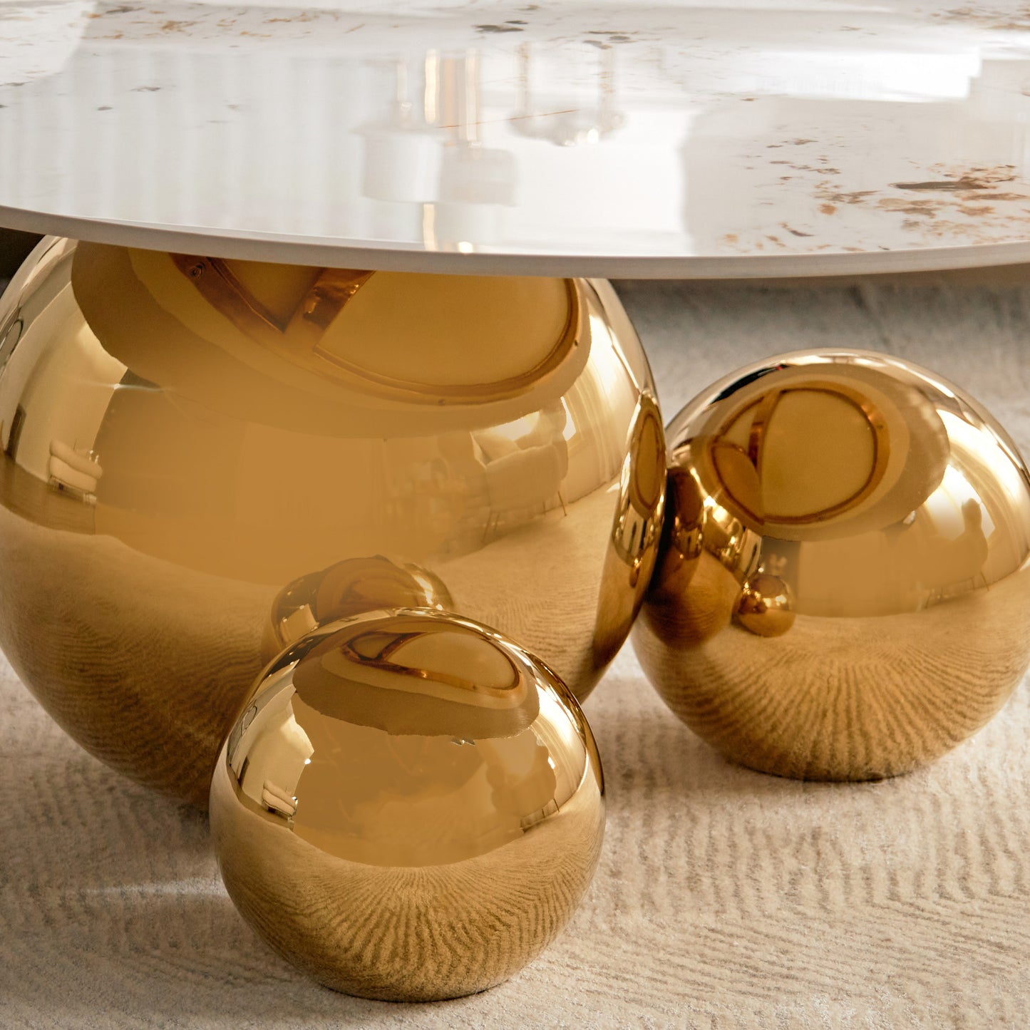 Gold spherical table legs on a textured surface with a marble top.