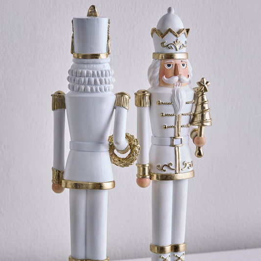 Decorative nutcrackers with white and gold attire on a light gray background