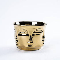 Gold-colored face-shaped candle holder on a white background