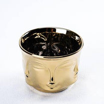 Gold-colored cup with face design on a white background