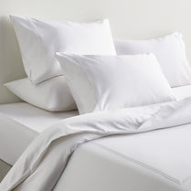 White bedding set with pillows on a neutral background