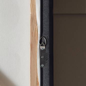 Close-up of a wooden frame with a metal hinge on a plain background