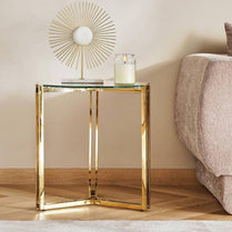 Gold side table with a candle and decorative mirror in a room setting.