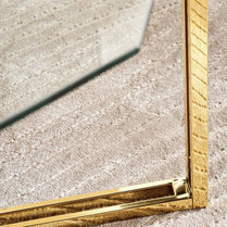 Gold-framed mirror corner on a textured surface