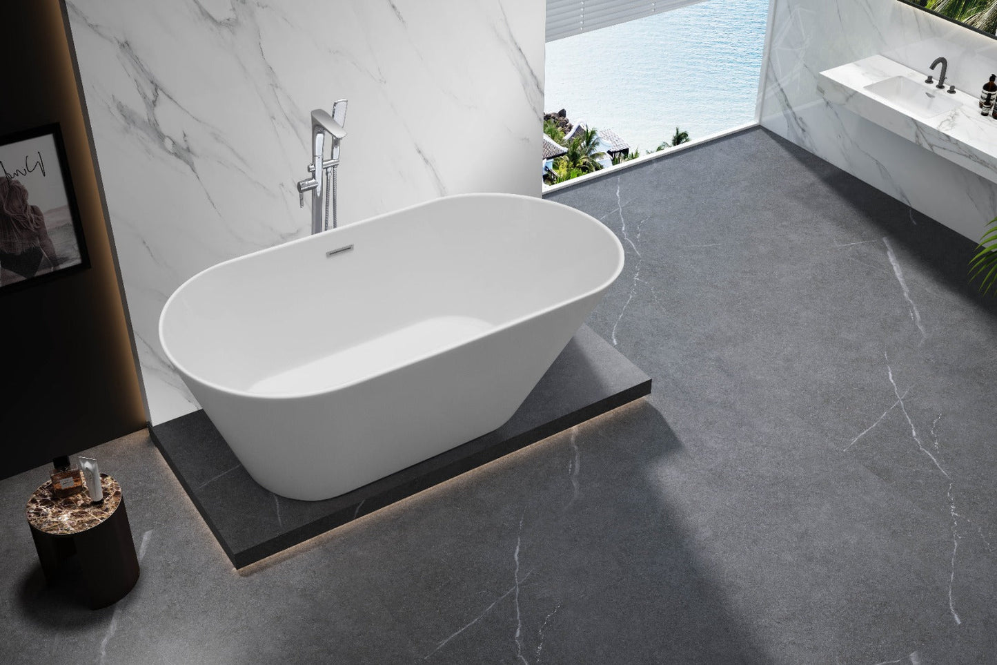 Modern bathroom featuring an acrylic freestanding bathtub on a raised platform, with gray stone flooring, marble walls, and a large window overlooking water. A sink and potted plant are visible in the background.