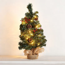 Small decorated Christmas tree with lights and pinecones on a plain background