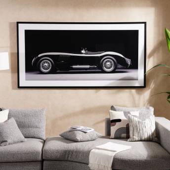 Framed artwork of a classic car on a wall above a gray sofa.