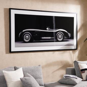Framed black and white photograph of a vintage car on a wall above a sofa.