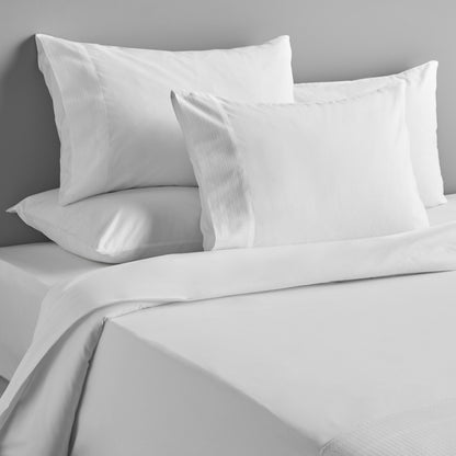 Gray bedding set with pillows on a bed against a gray wall.