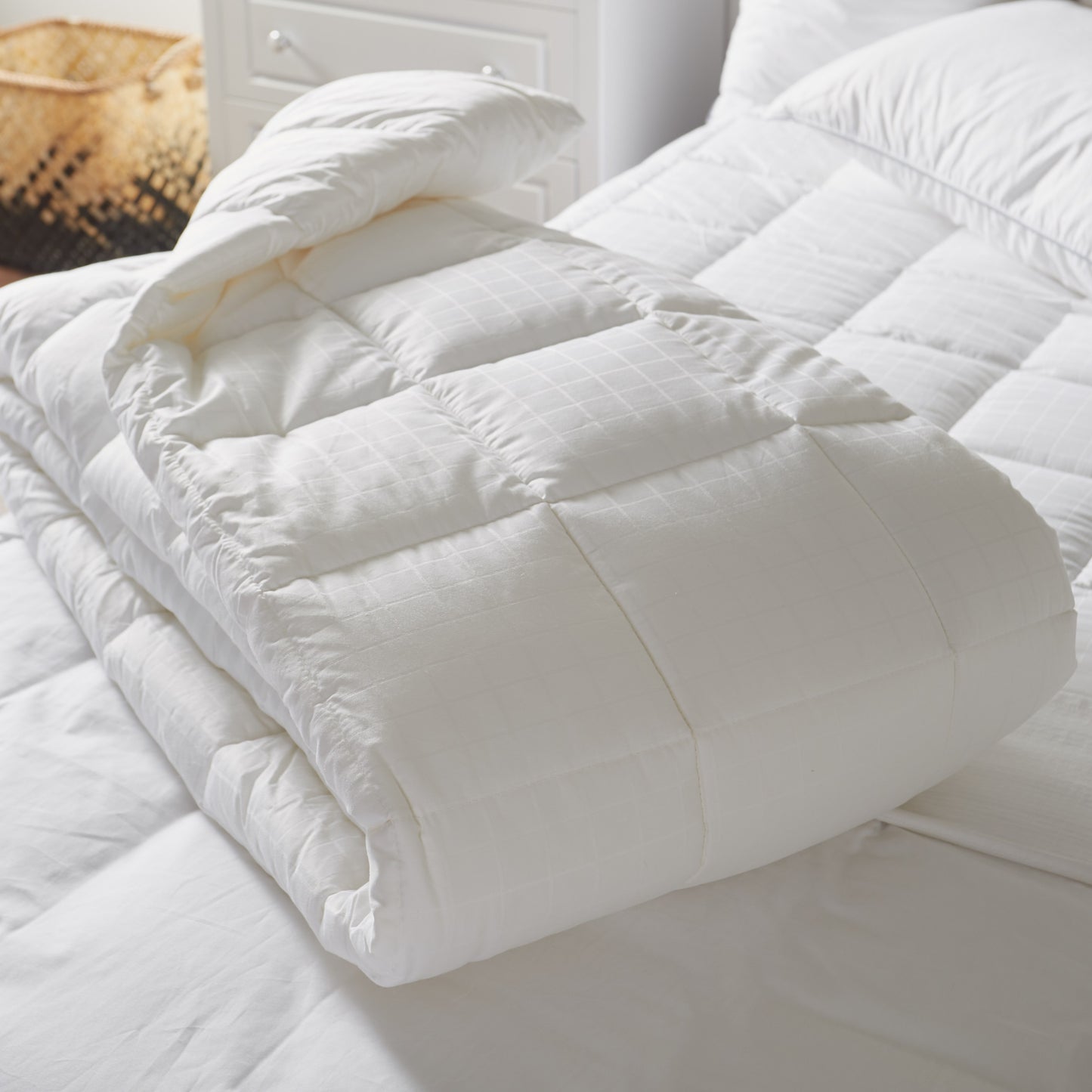 White quilted comforter on a bed with pillows