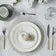 Elegant table setting with white plates, silverware, and a red napkin on a white tablecloth- Arabia 24-Piece Cutlery Set – Stainless Steel