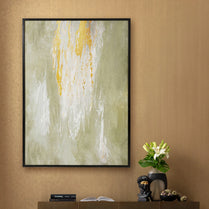 Framed abstract art piece on a wall with a vase of flowers and books below.