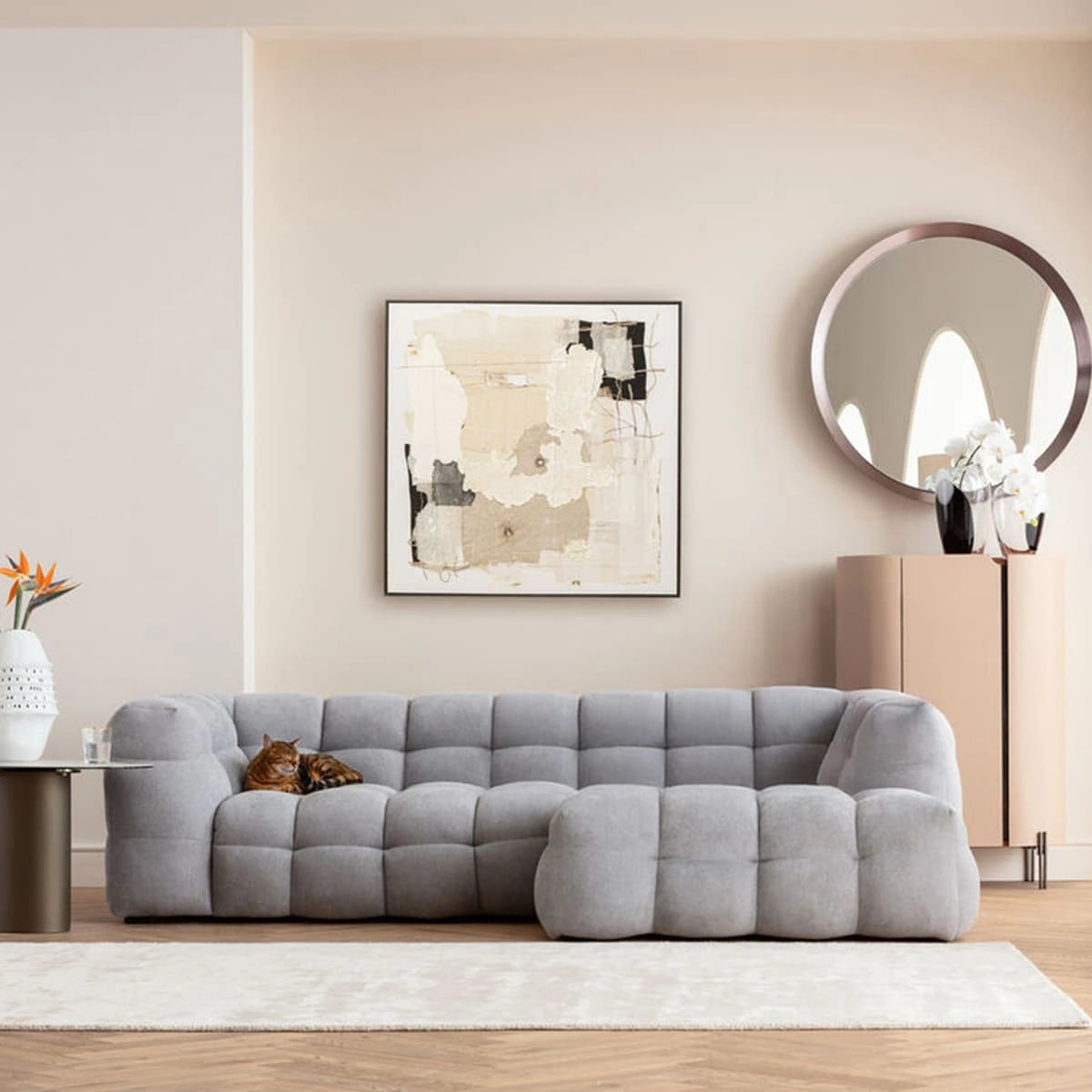 Gray sofa in a living room with abstract art and a mirror on the wall.