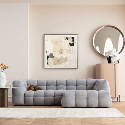 Gray sofa in a living room with abstract art and a mirror on the wall.