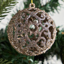Decorative ornament with intricate patterns hanging on a tree.