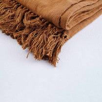 Brown woven blanket with fringes on a light gray background