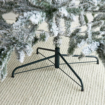 Black metal Christmas tree stand with a decorated tree on a textured surface