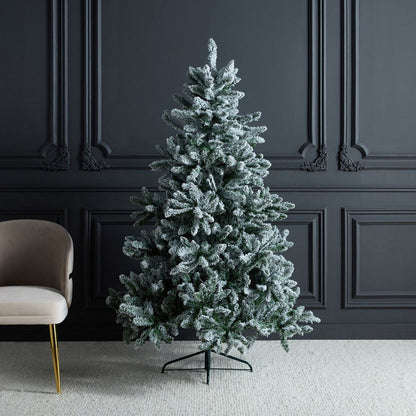 Frosted artificial Christmas tree in a room with dark paneled walls and a beige chair.
