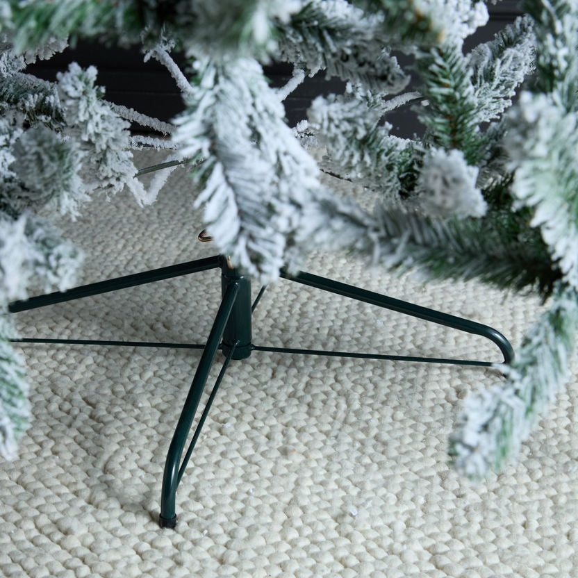 Frosty artificial Christmas tree on a stand with a textured beige surface background