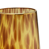 Close-up of a tortoiseshell-patterned glass with a gold rim on a white background