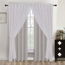 White curtains hanging in front of a window with a dresser and decor items in the background.