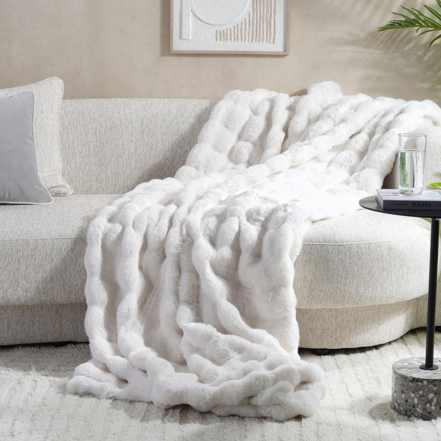 White textured blanket draped over a beige sofa in a living room setting.