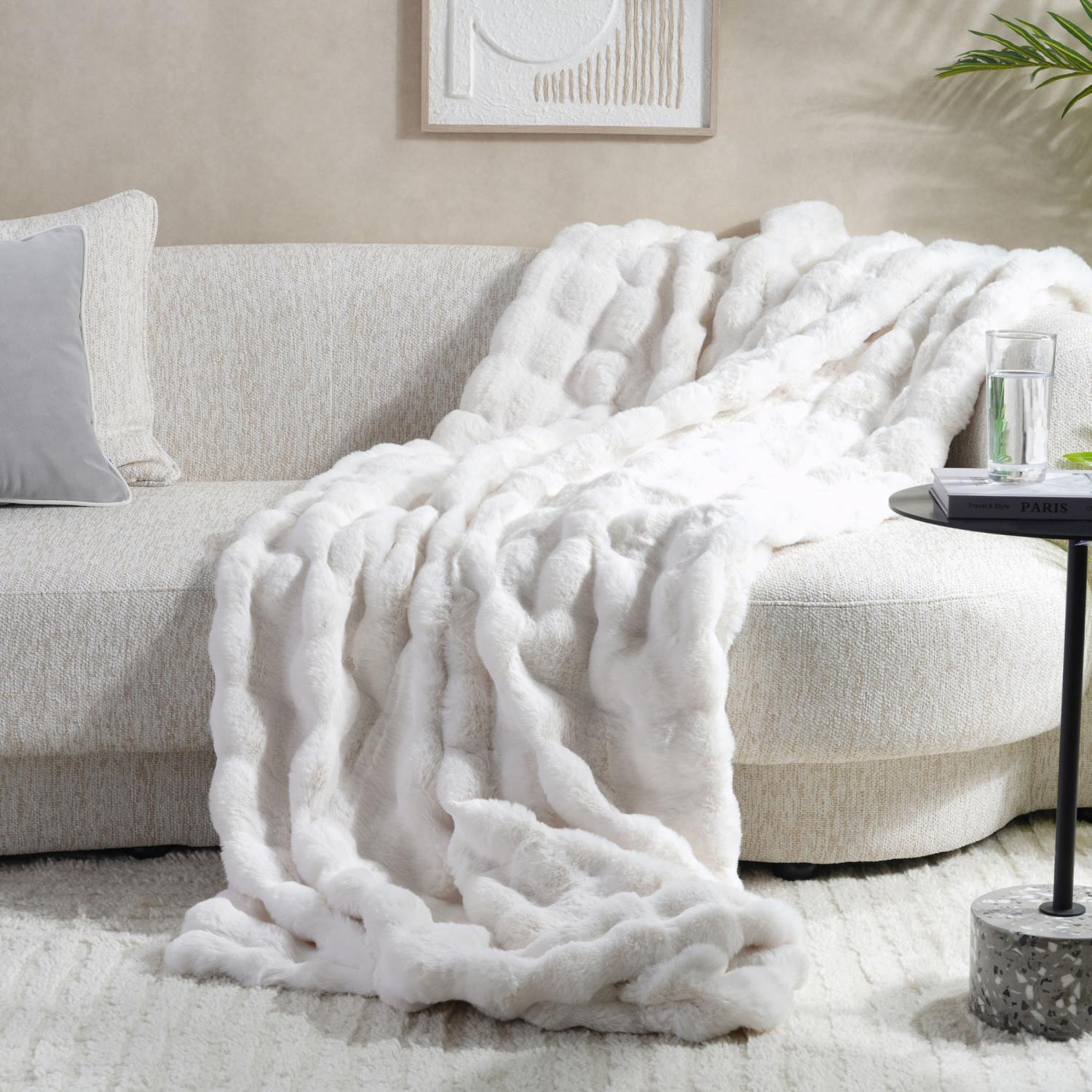 White textured blanket draped over a beige sofa in a living room setting.