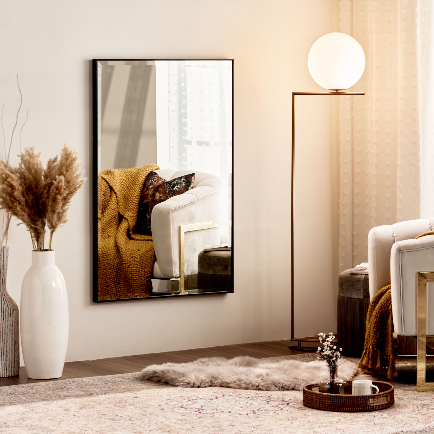 Living room with a large mirror reflecting a cozy corner, a lamp, and decorative items.