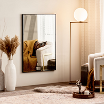Living room with a large mirror reflecting a cozy corner, a lamp, and decorative items.