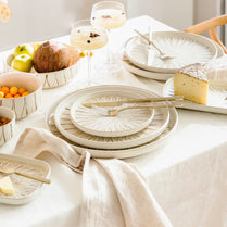 White ceramic plates and bowls on a table with fruits and cheese