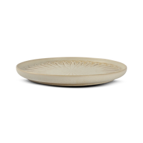 Beige ceramic plate with textured design on a white background
