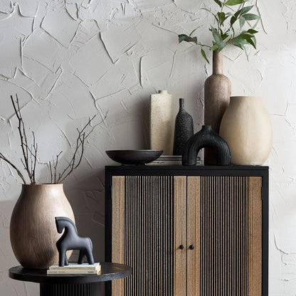 Decorative setting with vases, a cabinet, and a textured wall.