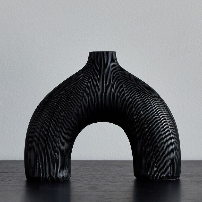 Black vase with arch design on a gray background