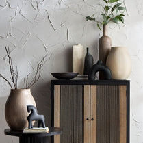Decorative setting with vases, a cabinet, and a textured wall.