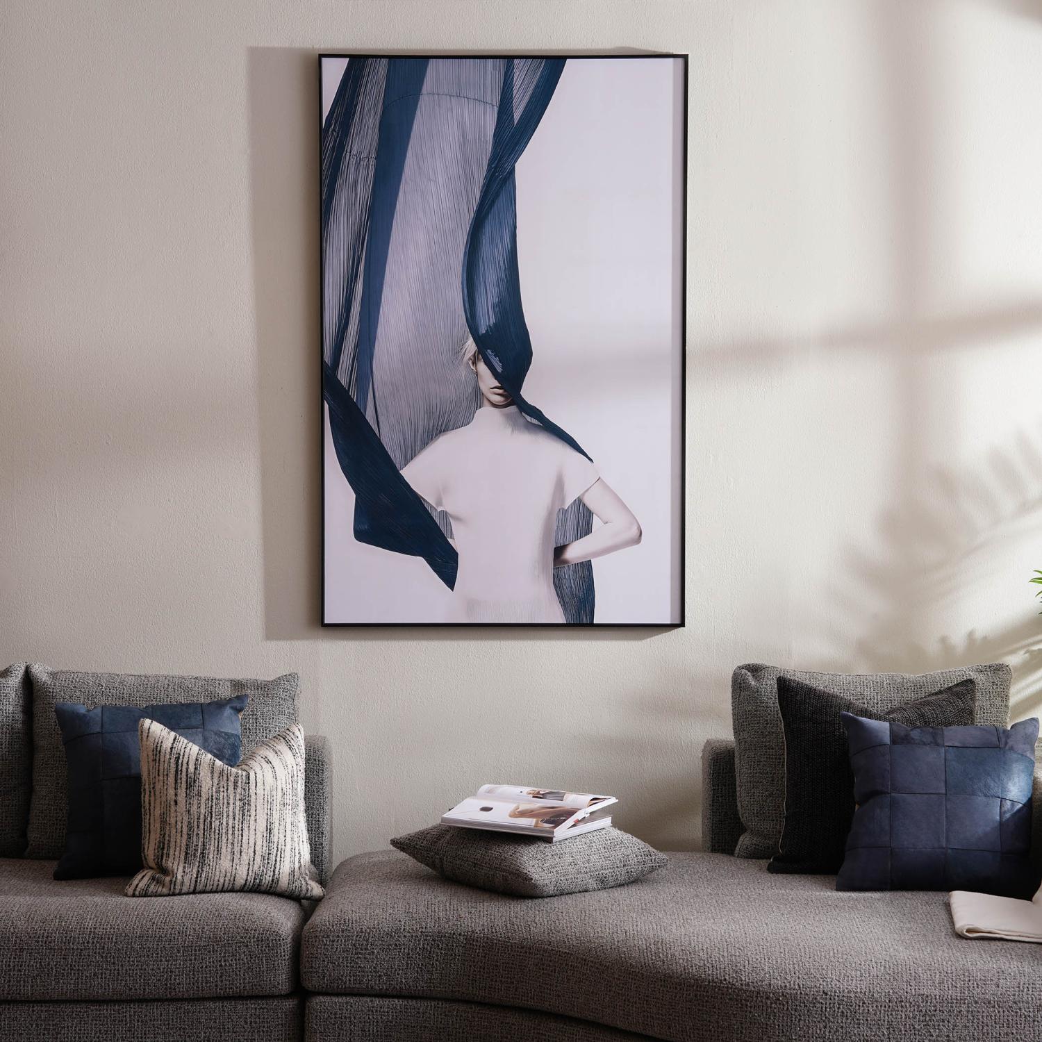 Gray sofa with decorative pillows and a framed abstract art piece on the wall.