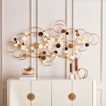 Decorative wall piece with circular designs on a white wall above a white cabinet.