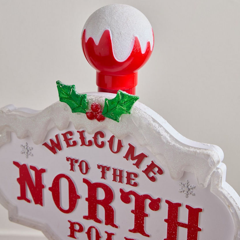 Decorative sign with 'Welcome to the North Pole' text and Christmas elements on a white background
