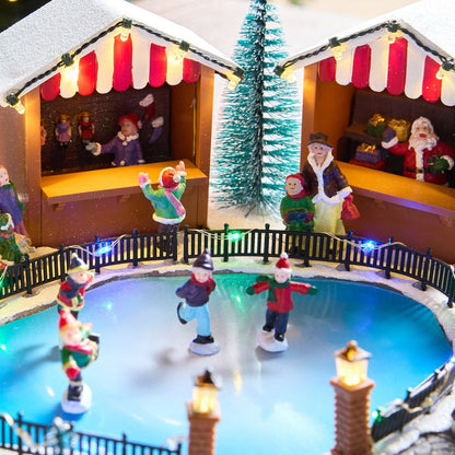 Miniature ice skating rink scene with figures and Christmas decorations.