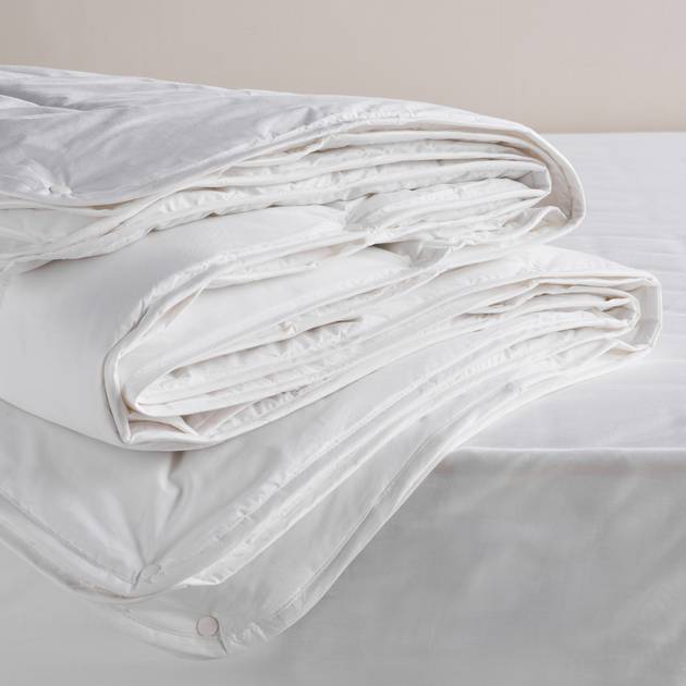 White comforter on a bed with a neutral background