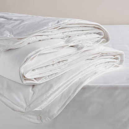 White comforter on a bed with a neutral background