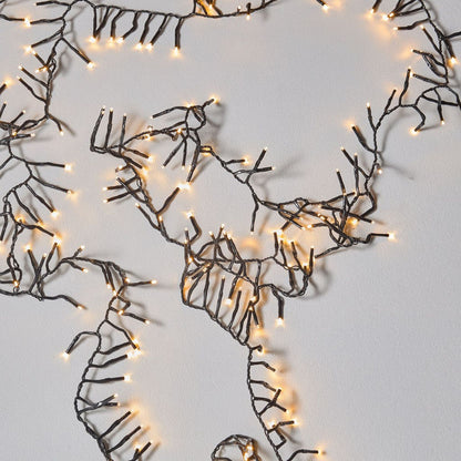 Decorative wall art with wire branches and string lights on a plain background