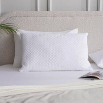 White textured pillow on a bed with a neutral headboard