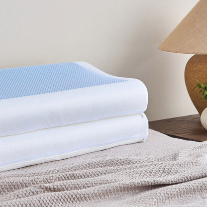 Stack of folded towels on a textured surface with a lamp and plant in the background.