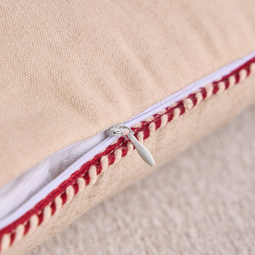 Close-up of a beige pillow with a red zipper detail on a beige background